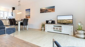 Una sala moderna con comedor, televisor de pantalla plana y obras de arte en las paredes.