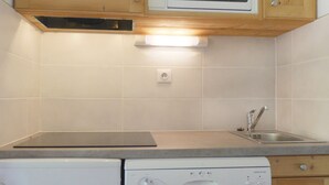 A kitchen with wooden cabinets, a microwave, a dishwasher, and a sink. - Cozy 2-Room Cabin, Southern Exposure, Ski-in/Ski-out, Pets Allowed (Méribel)