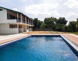 A swimming pool adjacent to a building with a balcony.