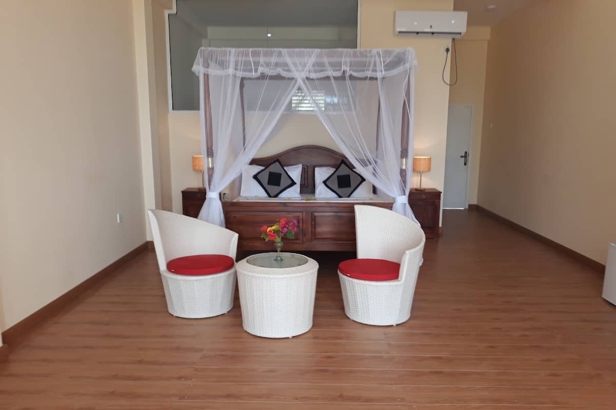 A bedroom with a bed, a nightstand, a bedside table, a chair, a small table, and a decorative item.