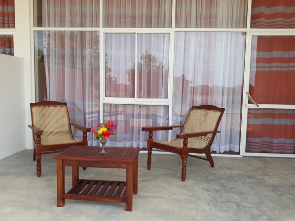 A room with two wooden chairs, a small wooden table, and a vase with flowers. - Flamingo Nature Resort (Weerawila)