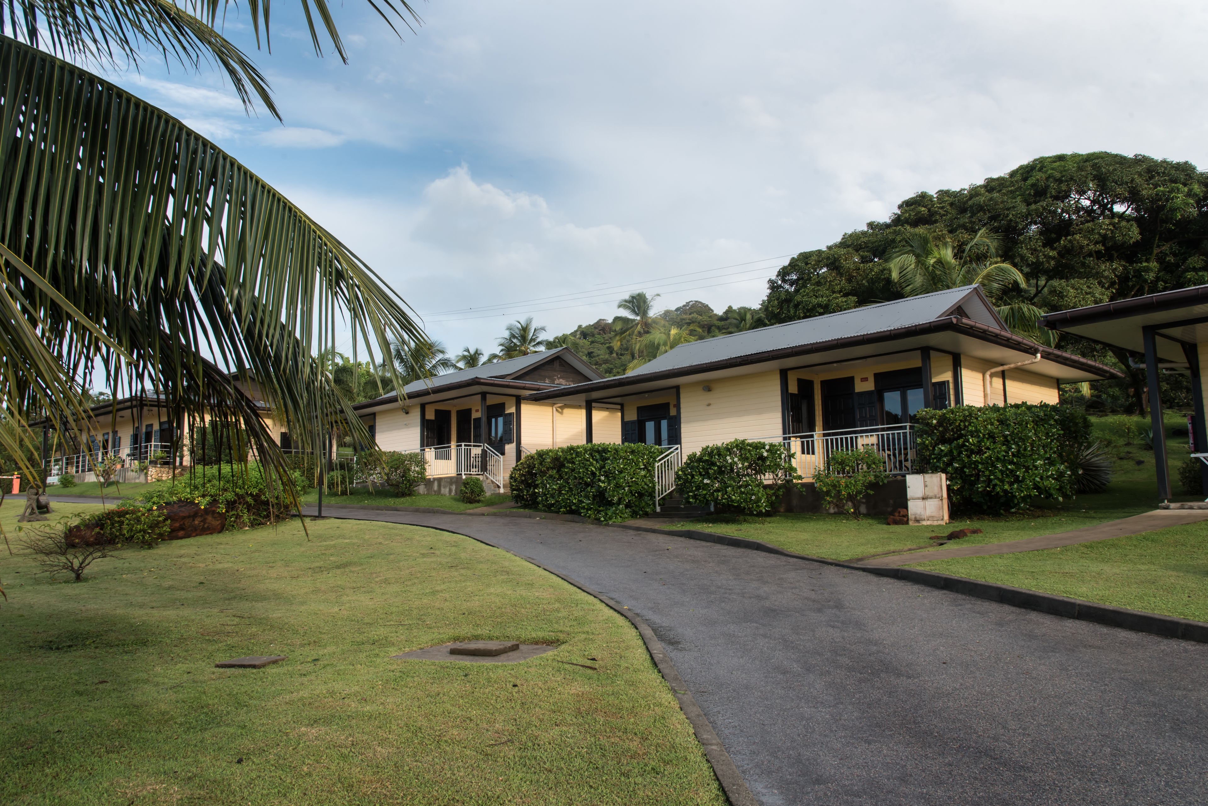 A row of two-story buildings with a curved driveway, surrounded by well-maintained lawns and palm trees.