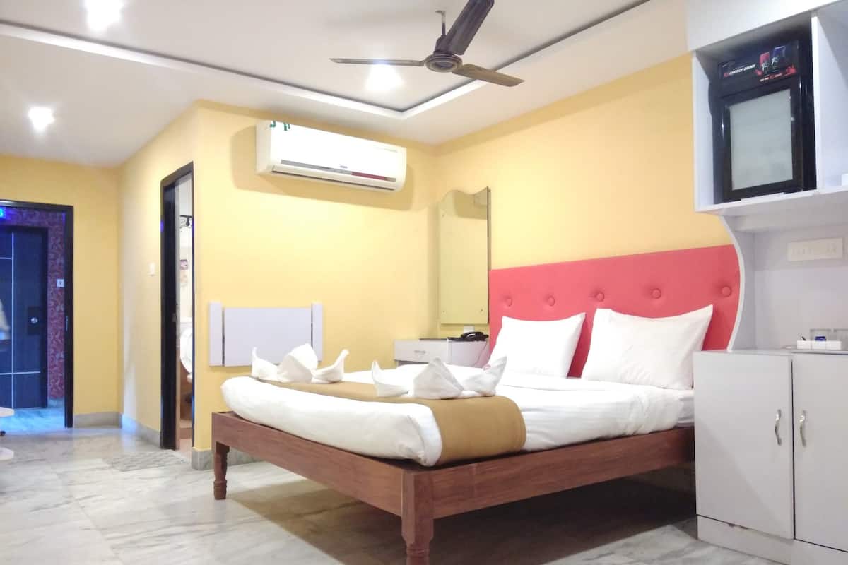 A hotel room with a bed, a wardrobe, an air conditioning unit, and a ceiling fan.