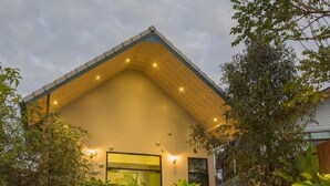 Een modern huis met een schuin dak, een veranda met treden en een grote olifantbeeld.