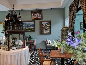 A dining area with a black and white patterned floor, a wooden table with a vase of flowers, and a bench with cushions.