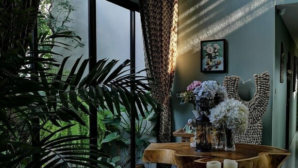 Een modern interieur met een ronde houten tafel, een bankje en potplanten.