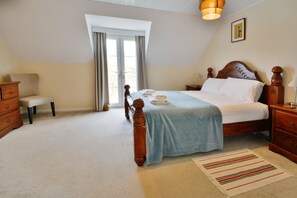 A bedroom with a bed, a nightstand, a dresser, a bench, and a window with curtains.