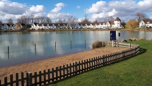 A lake with a wooden fence and a sign indicating swimming.