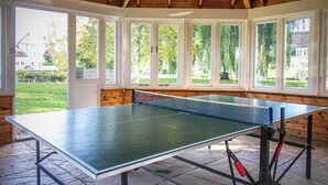 A ping pong table in a room with large windows and wooden walls.