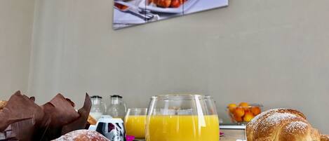 A breakfast table with croissants, orange juice, and a coffee cup.