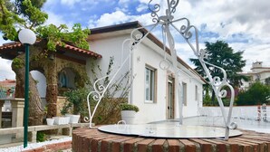 Un patio con una fuente de ladrillo, paredes blancas y un techo de tejas.