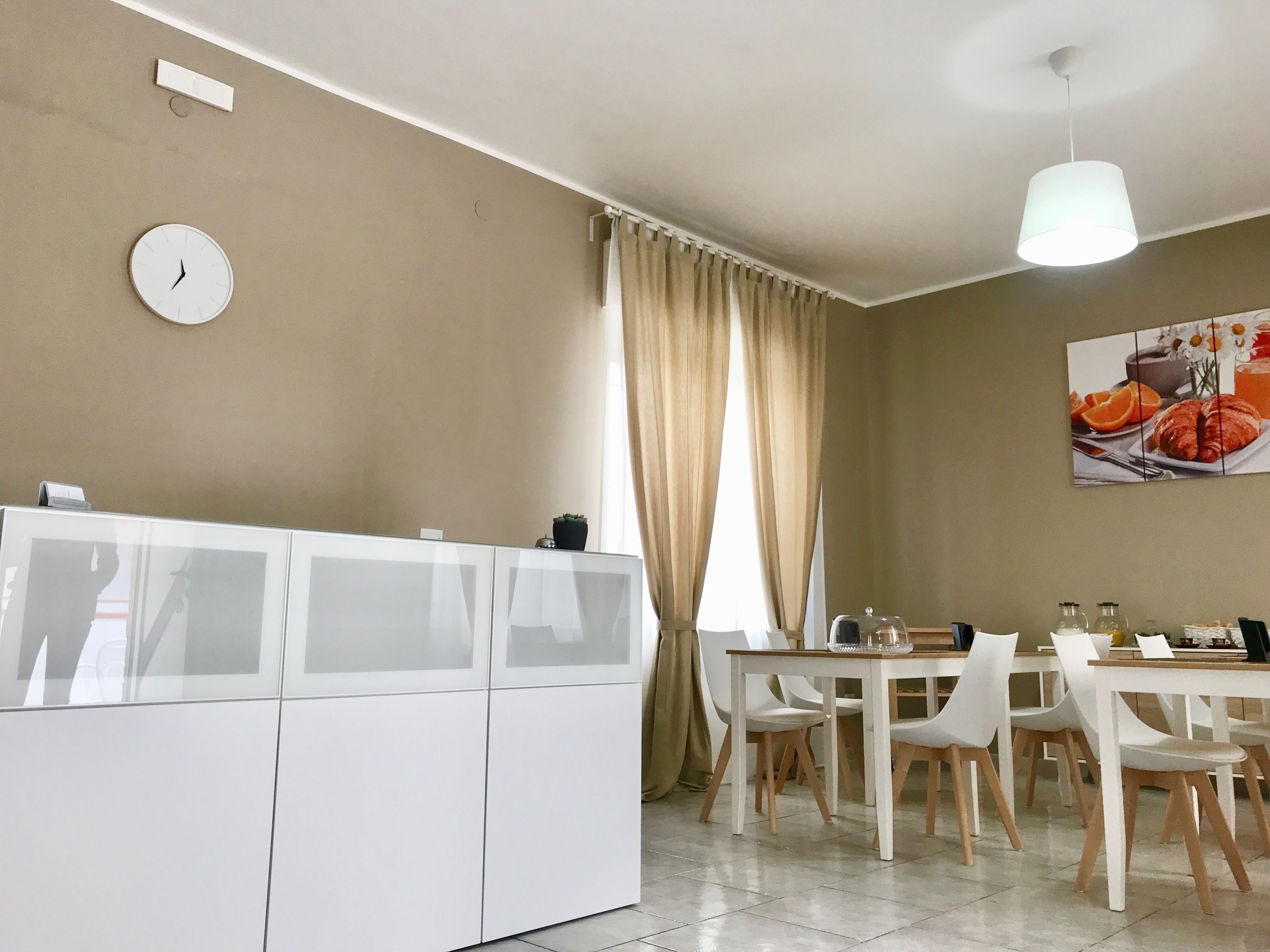 Una zona de menjador moderna amb un armari blanc, un rellotge i una taula preparada per dinar.