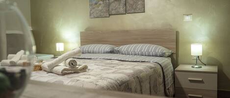 A hotel room with a bed, two bedside lamps, a nightstand, and a wall-mounted painting.