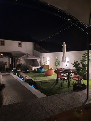 A covered outdoor area with a dining table and chairs, a blue bean bag, and a potted plant. - CASA DA ROSEIRA - your holiday home with private garden (Famalicão)