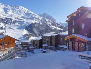 A snow-covered mountain village with wooden buildings and a ski lift.