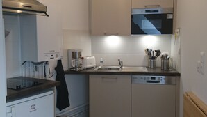 A compact kitchen with a built-in oven, microwave, and dishwasher. - Emerald Coast Studio  (Saint-Méloir-des-Ondes)
