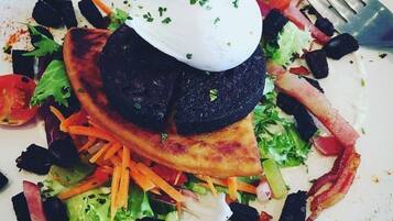 Un plato de comida con varios vegetales, un trozo de carne y una cucharada de salsa.