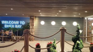 A reception area with a 'Welcome to Duck Bay' sign, a stone pillar, and a rope barrier. - Duck Bay Hotel (Alexandria)