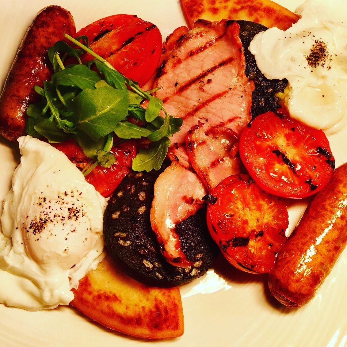 A plate of food with grilled tomatoes, sliced meat, and a poached egg.