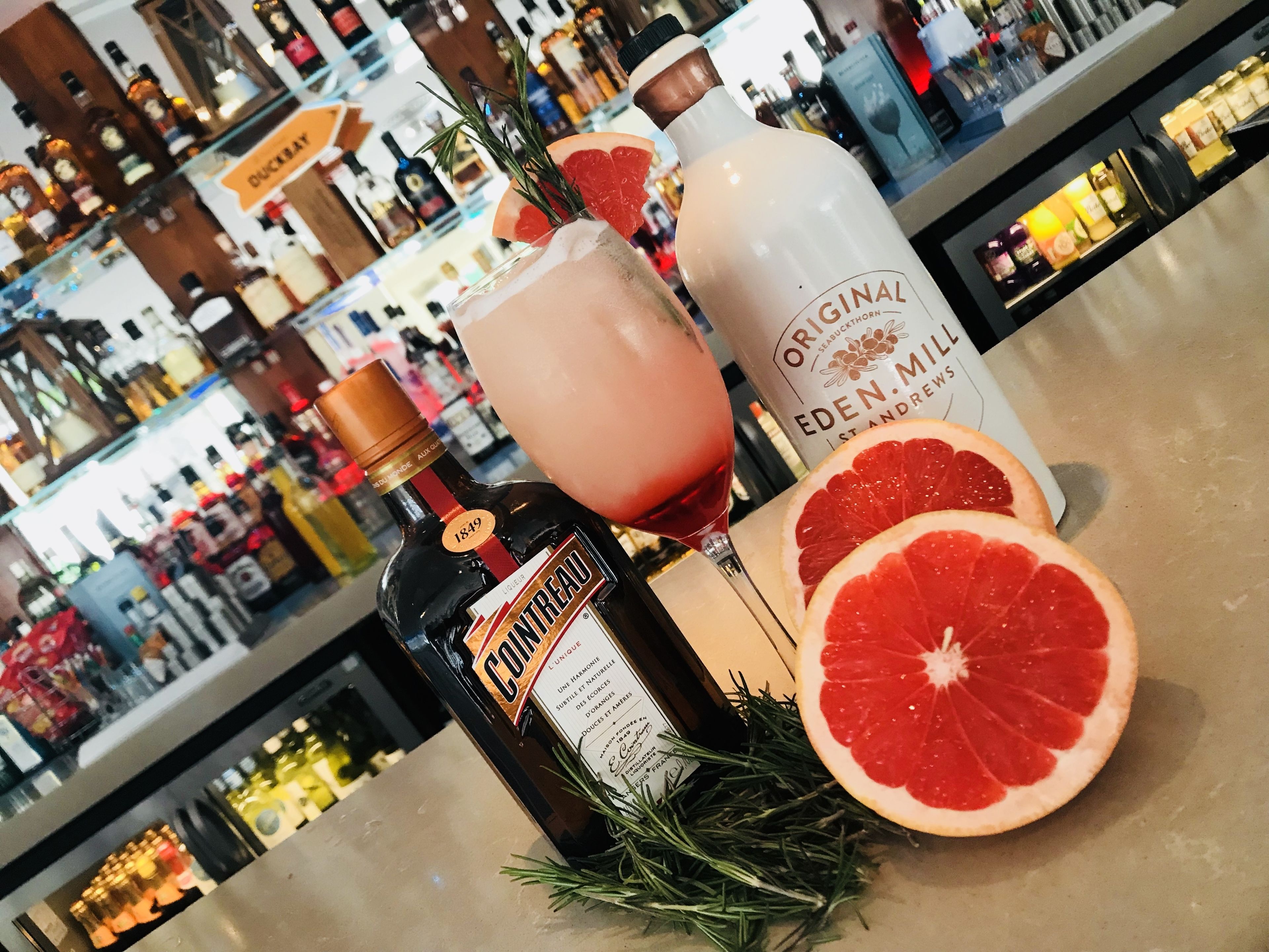Eine Bar mit Flaschen und Gläsern, darunter eine Cointreau-Flasche und eine Flasche Original Gin.