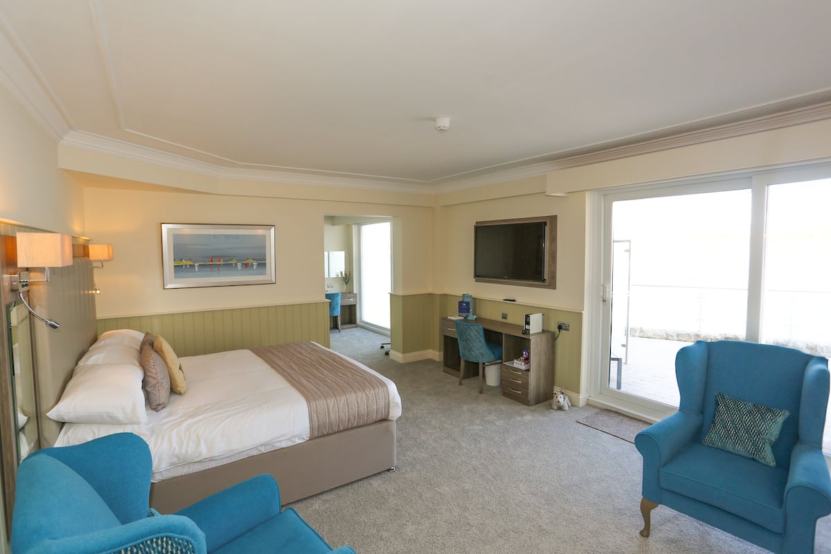 A hotel room with a bed, a desk, a chair, and a TV.