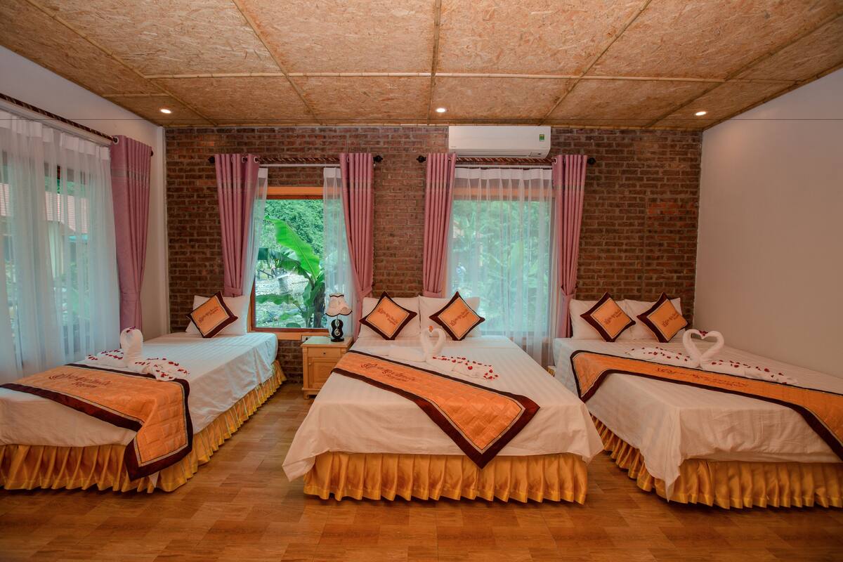 Une chambre d’hôtel avec deux lits, un mur en briques et une vue sur la verdure.