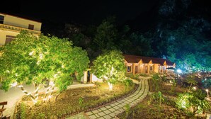 Un chemin bien éclairé qui mène à un bâtiment entouré d’une végétation luxuriante.
