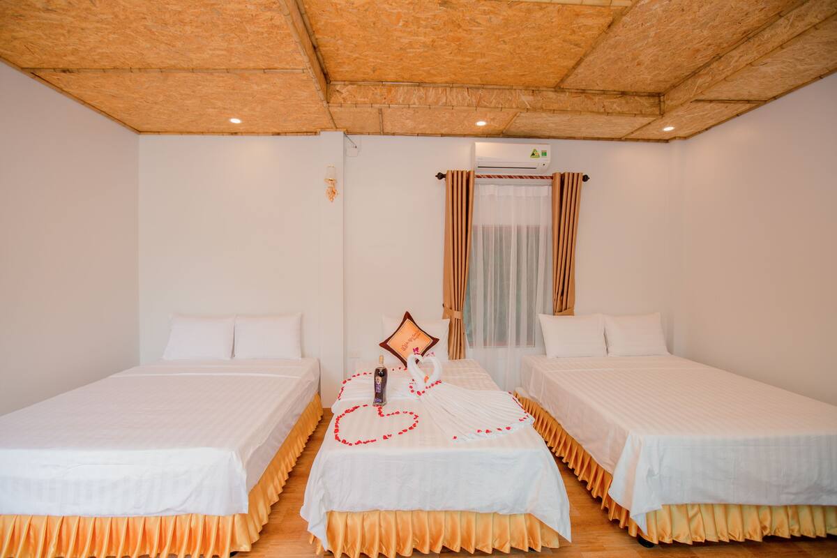Une chambre d’hôtel avec deux lits simples, un plafond en bois, un appareil de climatisation et une fenêtre avec des rideaux.