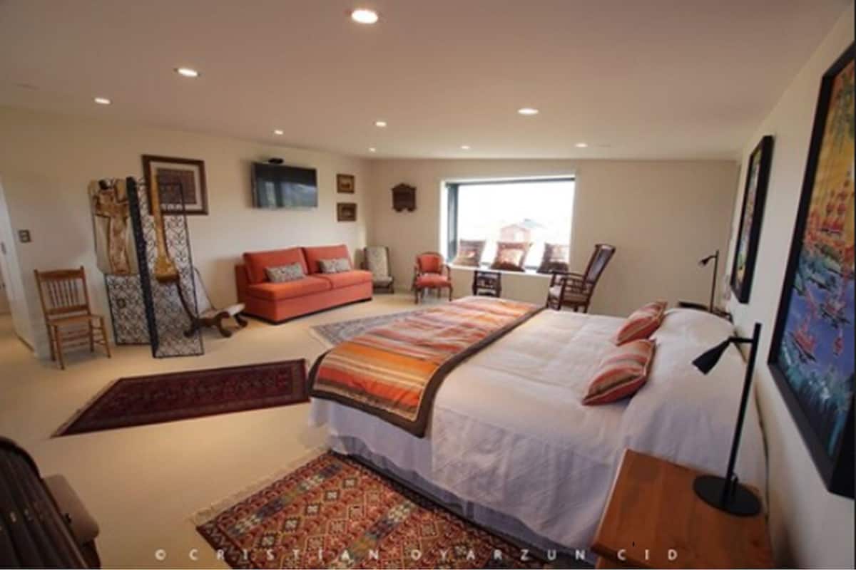 Une chambre à coucher avec un lit, un canapé, une chaise, un bureau et une fenêtre.