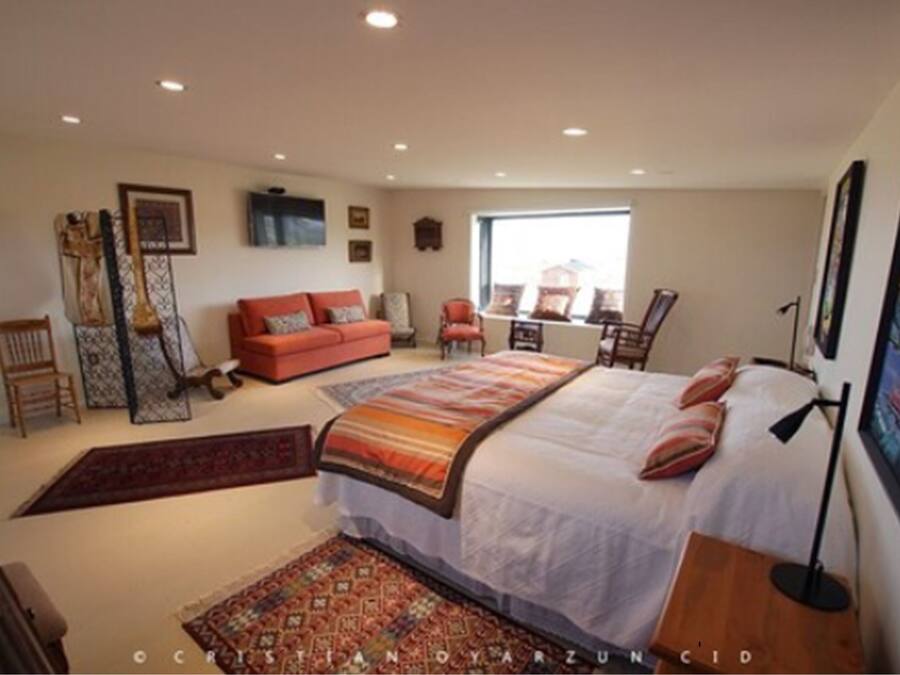 A bedroom with a bed, a sofa, a chair, a desk, and a window.