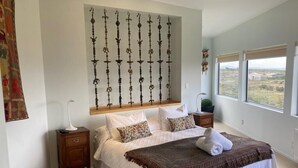 Un dormitorio con una cama grande, una mesita de noche, un adorno en la pared y una ventana con vistas.