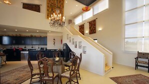 Un espacio habitable amplio con una mesa y sillas de comedor, una escalera y una cocina al fondo.