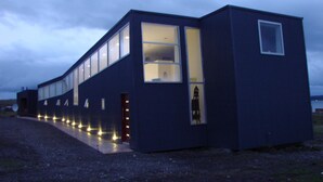 Un edificio moderno con ventanas amplias y una entrada pequeña.