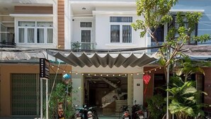 A multi-story residential building with balconies, a covered entrance, and parked motorcycles. - 10 Dollar Homestay Danang - Hostel (Da Nang)