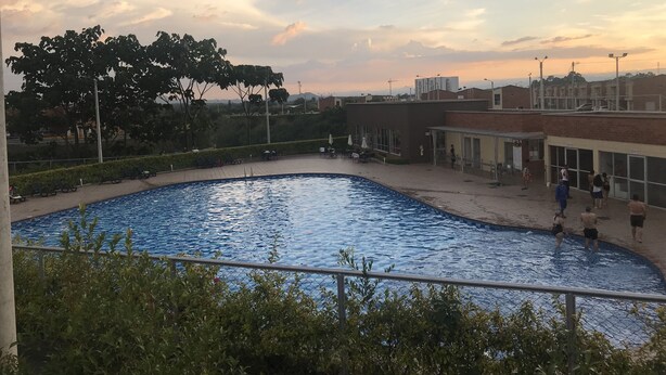 A swimming pool surrounded by a fence, with a few people around it. - Pereira-Cerritos Casa (Pereira)