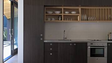 A modern kitchen with dark wood cabinets, a stainless steel oven, and a built-in shelf with dishes.