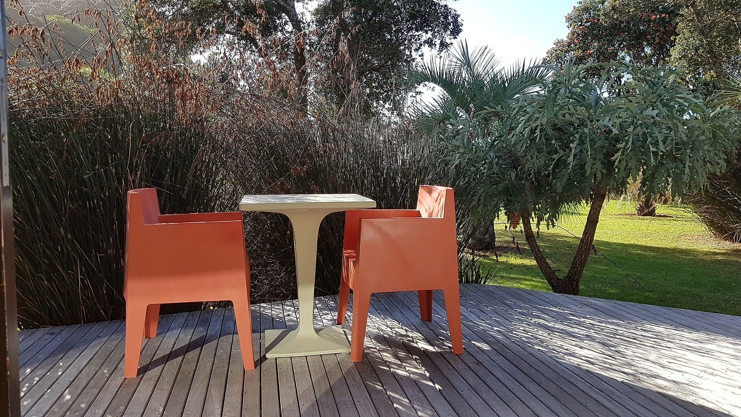 Ein Sitzbereich im Freien mit Tisch und zwei Stühlen auf einer Holzterrasse.
