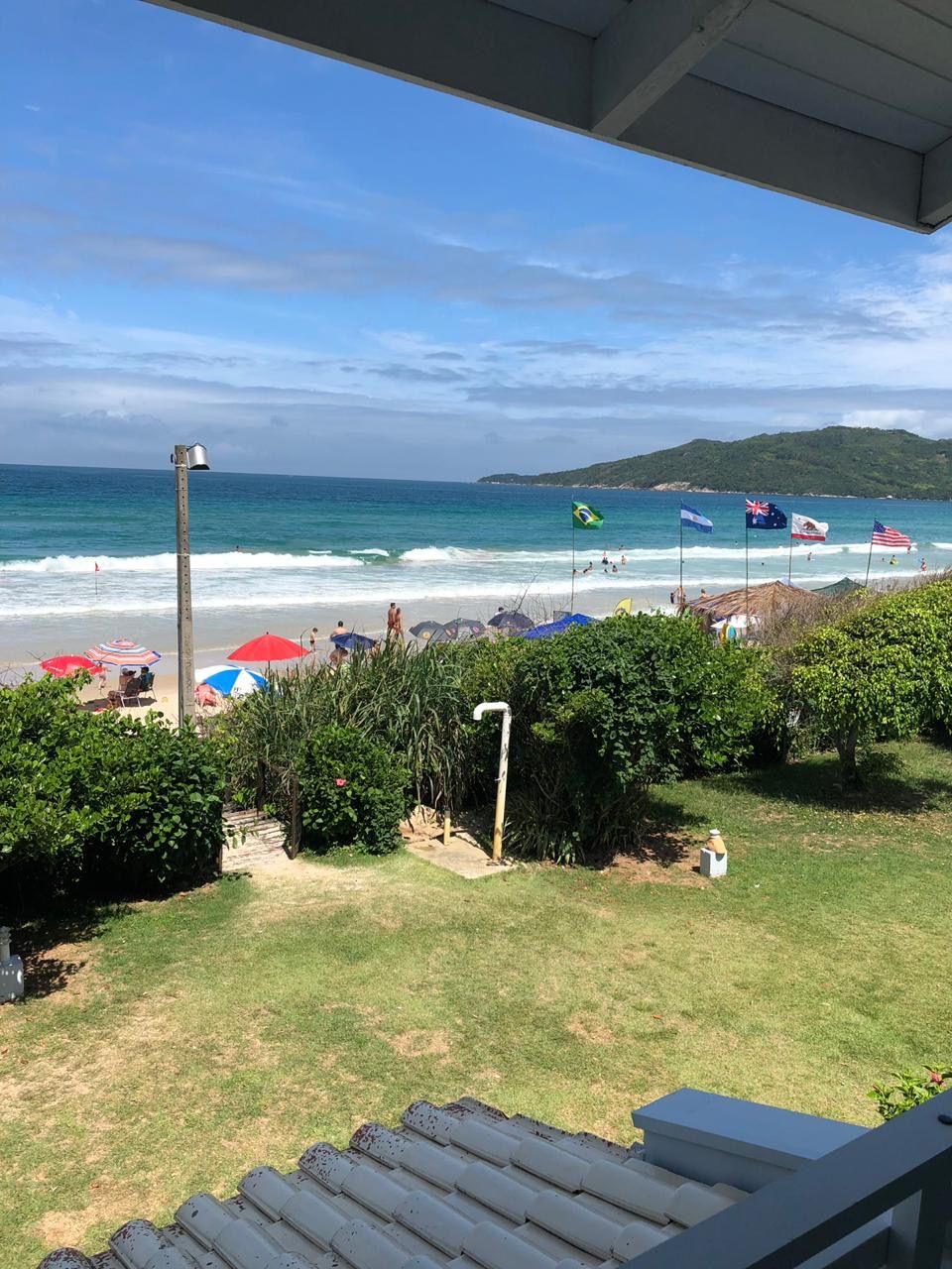 A beach view with umbrellas, flags, and a clear sky.