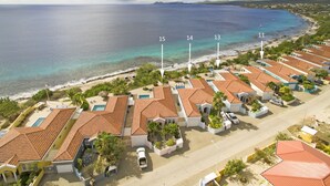 A coastal resort with multiple bungalow-style buildings, each with a private pool and direct ocean views.