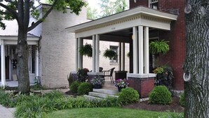 A brick building with a covered porch, steps, and potted plants. - The Martin House - In the heart of historic downtown Lexington (Lexington)