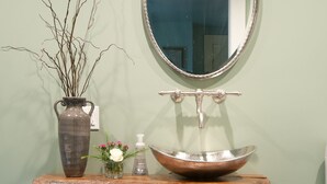 A bathroom vanity with a mirror, a vase with branches, a bowl sink, and rolled towels. - The Martin House - In the heart of historic downtown Lexington (Lexington)