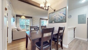 Zona pranzo con tavolo e sedie di legno, un divano e un camino. Sulla parete, una mappa di Mammoth Mountain.