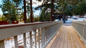 Une terrasse en bois, dotée de rampes, qui mène à un bâtiment avec un escalier.