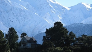 A house with a sloped roof, surrounded by trees and snow-covered mountains. - NOT JUST A STAY,  we are a stay you will remember! (Kaikoura Township)