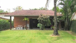 A house with a tiled roof, a front porch, and a lawn.