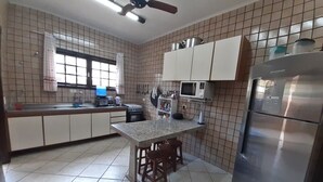 A kitchen with a central island, white cabinets, a stainless steel refrigerator, and a ceiling fan.