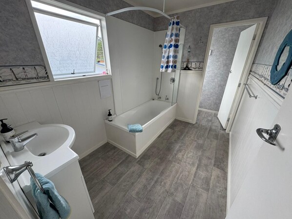 Un bagno moderno con vasca, doccia e lavandino.