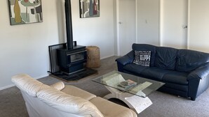 Ein Wohnzimmer mit einer Couch, einem Glastisch, einem Kamin und zwei Türen.