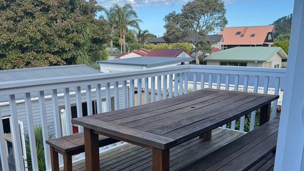 Eine Holzterrasse mit Tisch und Bänken, umgeben von einem weißen Geländer.