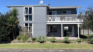 Ein zweistöckiges Haus mit Balkon, Satellitenschüssel und einem kleinen Garten mit verschiedenen Pflanzen.
